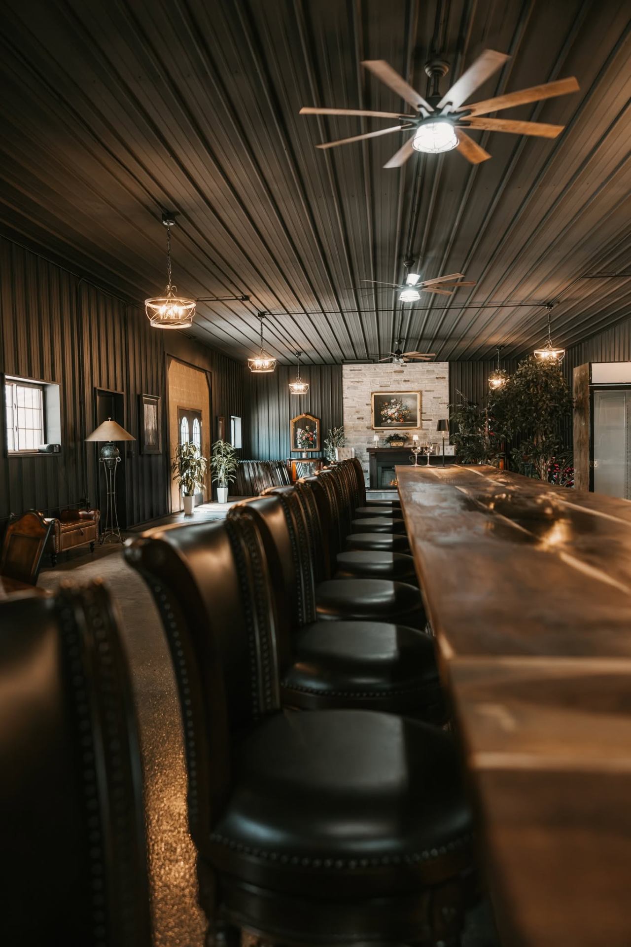 Bar with leather stools, pendant lighting, and the stone fireplace in the distance