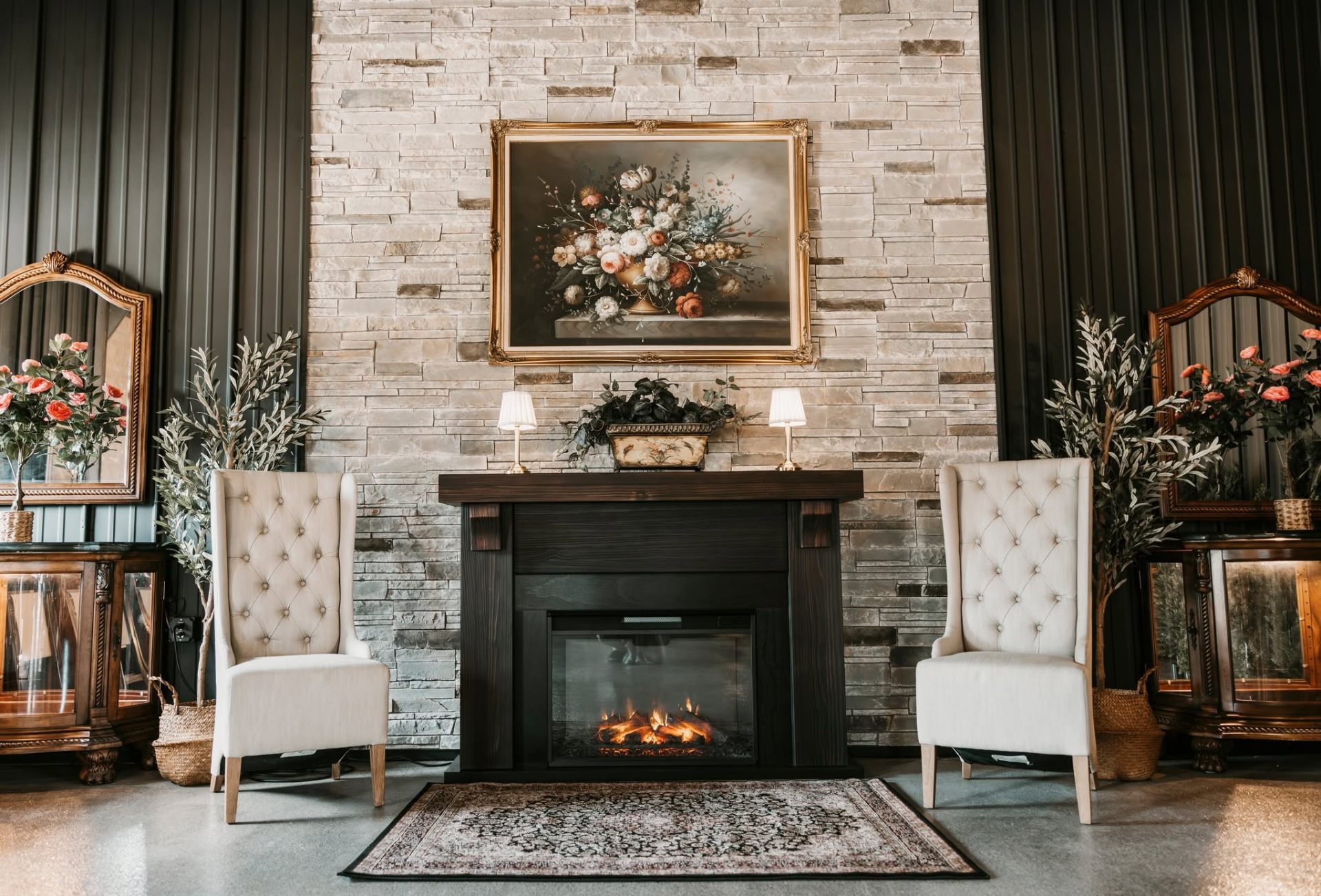 Stacked stone fireplace flanked by tufted wing chairs and gold-framed floral art